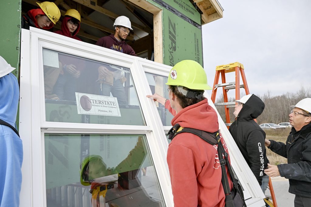 Several students list a window into a building.