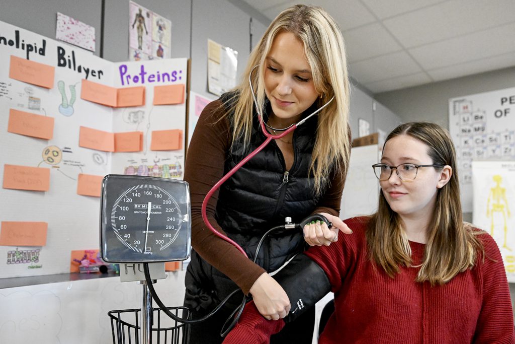 A nursing student takes the blood pressure of another student.