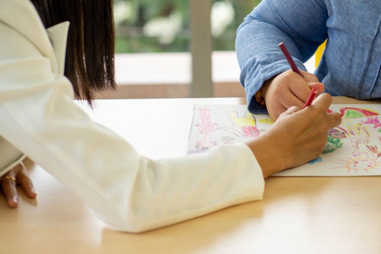 A student coloring with a teacher.
