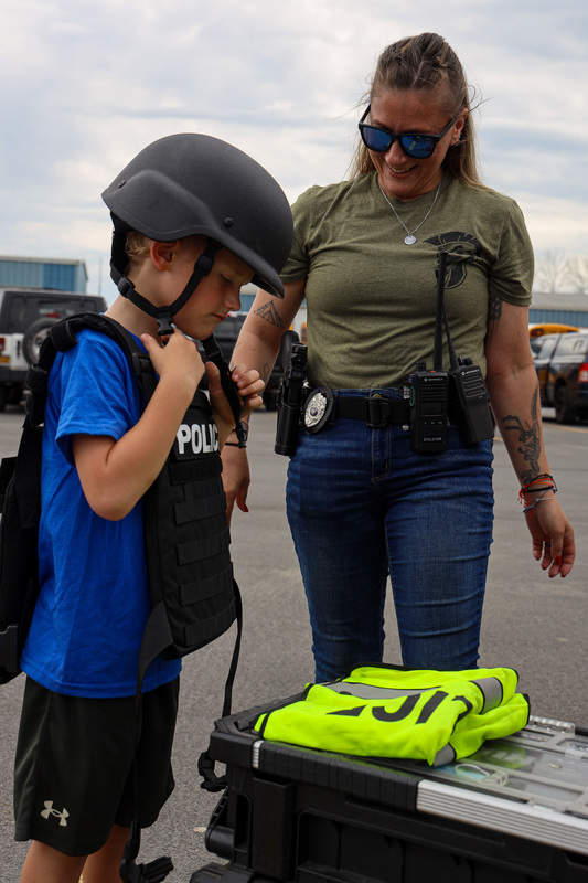 kindergartener tries on police vest and helmet