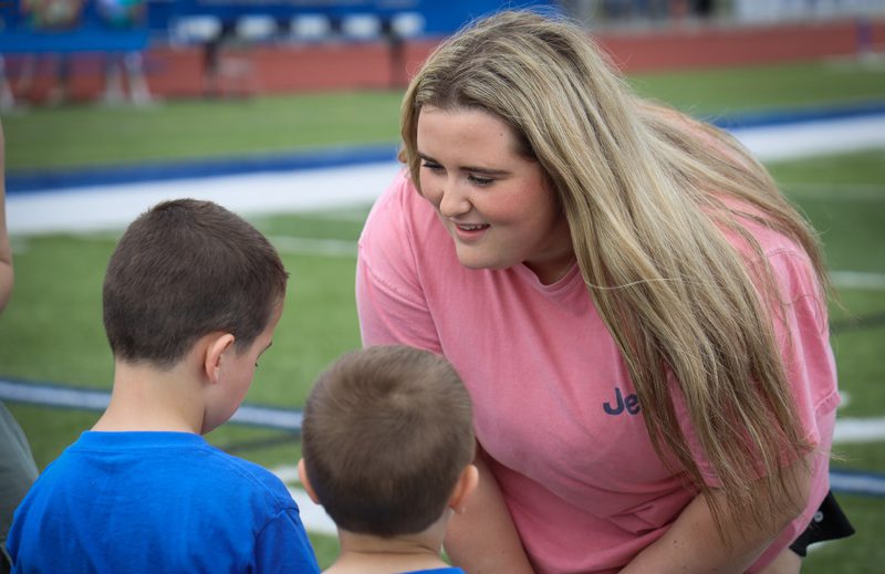 A teacher leans over to chat with a small child.