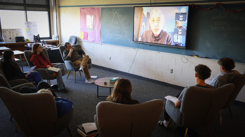 class sits in circle while participating in a video call