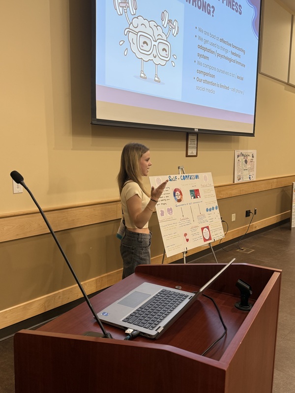 Student stands next to display while presenting