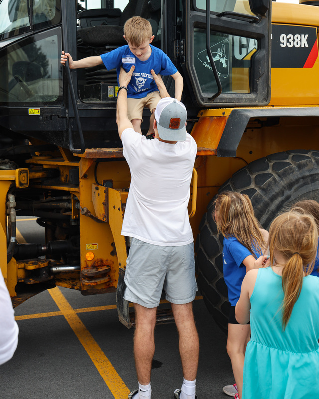 senior helps kindergartener out of construction vehicle