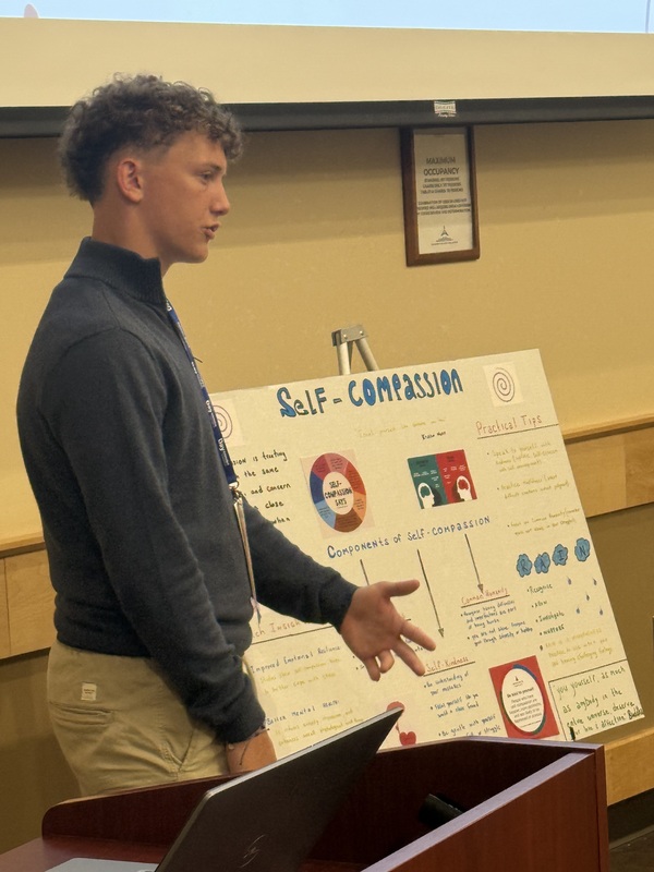 Student presenting next to display of self-compassion