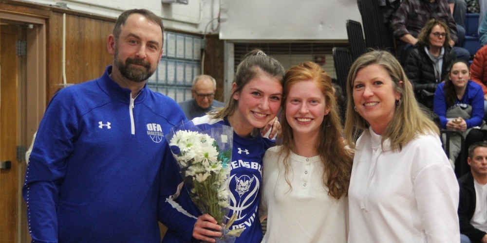 Former OFA Basketball Coach, Mark Henry with two students and another adult in a gym setting.
