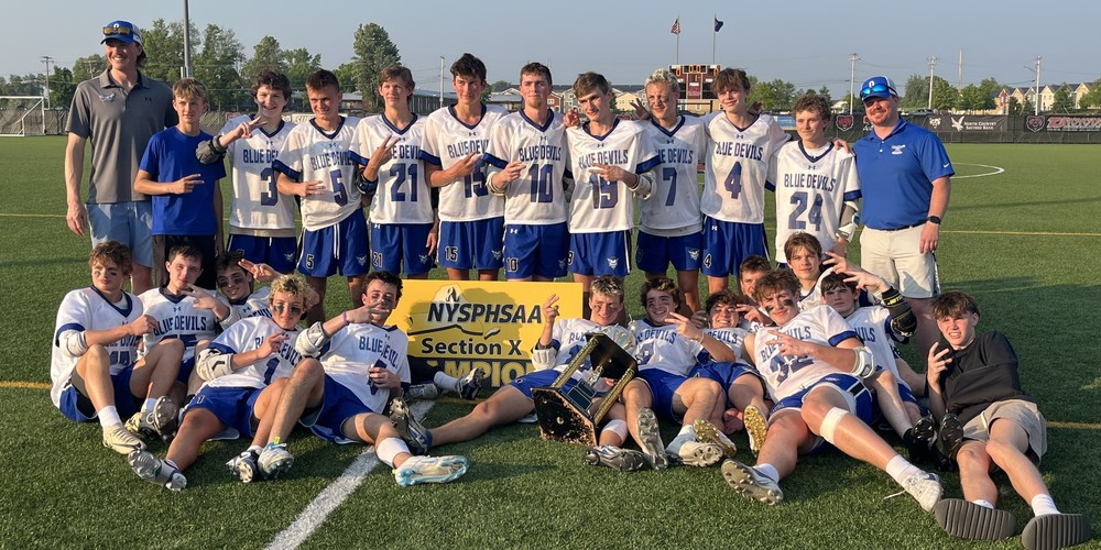 The boys varsity lacrosse team surrounding a sign that say "Section X Champions".