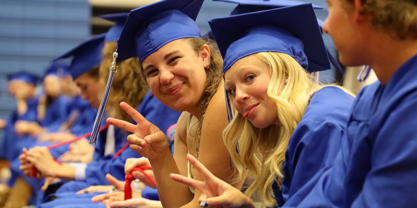 Two graduates seated in a row during graduation.