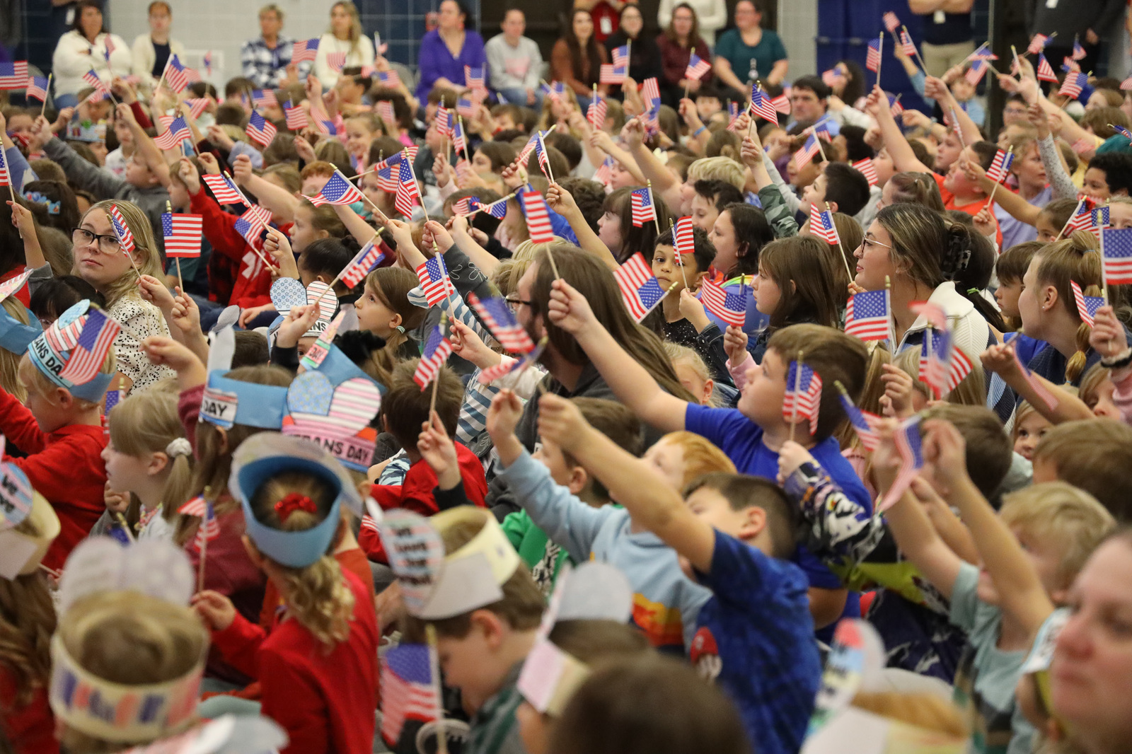 Many young students raise miniature flags in the air.